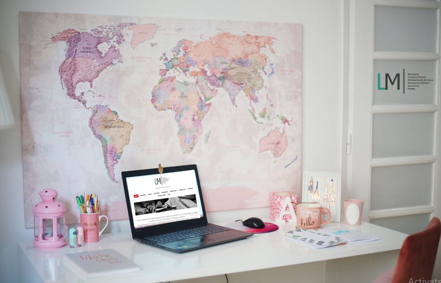 Laptop on desk in front of pink world map