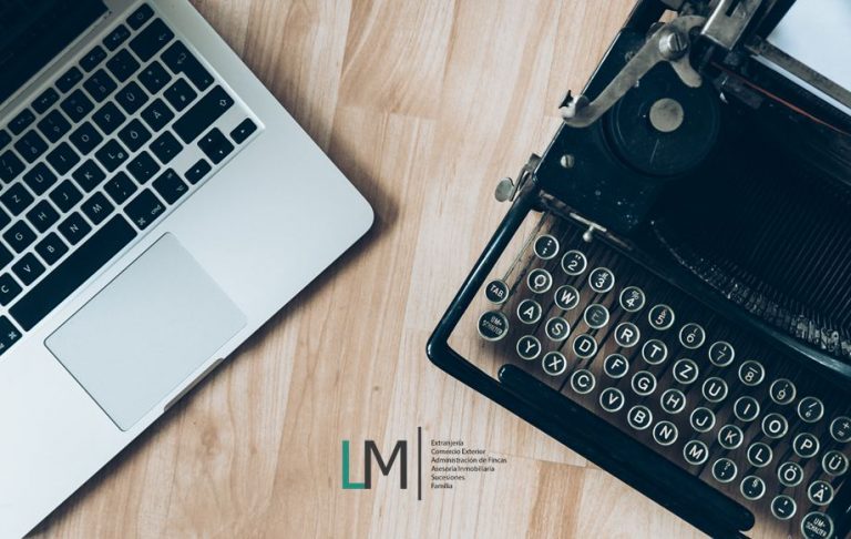 Laptop & typewriter on table & LM Abogados logo