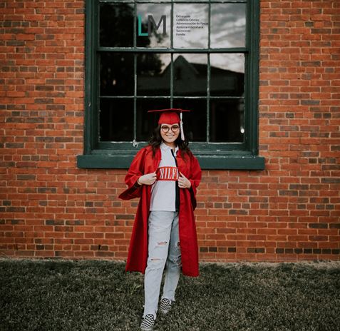 Graduating student in red in front of window & LM Abogados logo